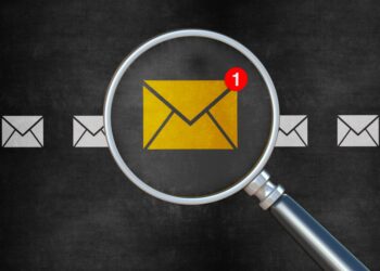 Graphic of a row of envelopes with one yellow envelope enlarged under a magnifying glass