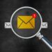 Graphic of a row of envelopes with one yellow envelope enlarged under a magnifying glass