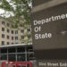 Photo of a sign for the Department of State in the foreground, with the building in the background