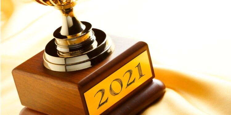 Trophy with engraved "2021" plaque, all against a yellow satin background