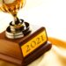 Trophy with engraved "2021" plaque, all against a yellow satin background