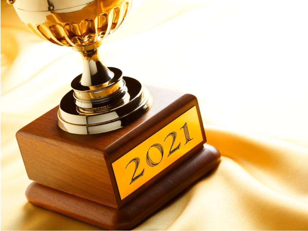 Trophy with engraved "2021" plaque, all against a yellow satin background