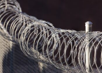 Close-up photo of a fence with razor wire on top of it