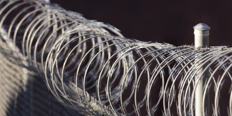 Close-up photo of a fence with razor wire on top of it