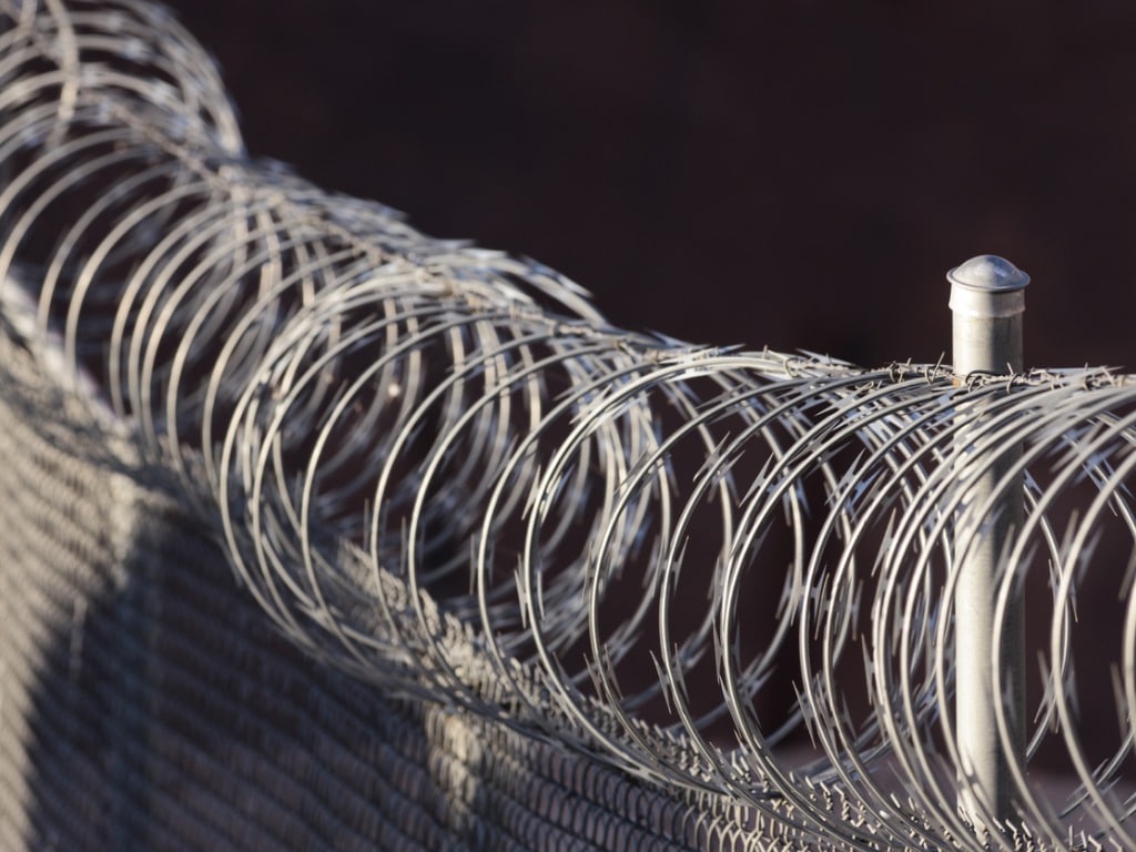 Close-up photo of a fence with razor wire on top of it