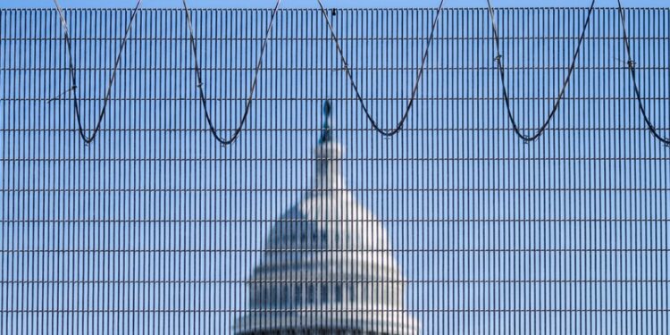 Photo of the U.S. Capitol building in the middle, with the blurry fence in the immediate foreground