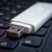 Photo of a white USB drive sitting on a black laptop keyboard