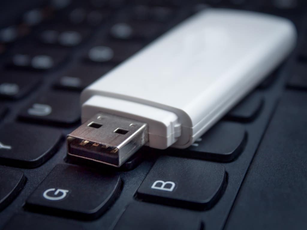 Photo of a white USB drive sitting on a black laptop keyboard