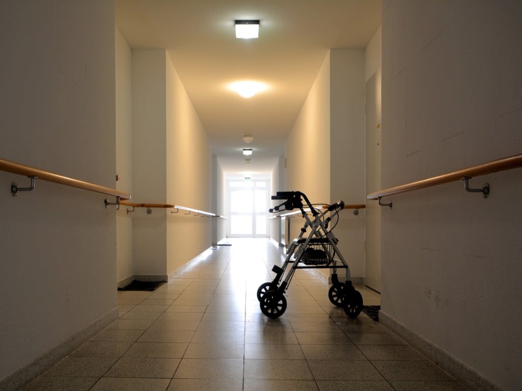 Photo of a dark hallway with minimal lighting with a walker stationary in the hallway