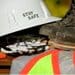 Hard hat with the words "Stay Safe" on it, with work boots, safety goggles, and a fluorescent vest