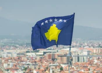 Photo of the Kosovo flag with a blurry picture of the city in the background