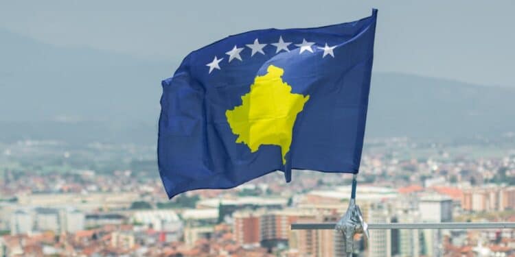 Photo of the Kosovo flag with a blurry picture of the city in the background