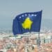Photo of the Kosovo flag with a blurry picture of the city in the background