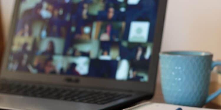 Photo of an online meeting with a cup of coffee and a notebook sitting nearby