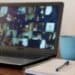 Photo of an online meeting with a cup of coffee and a notebook sitting nearby