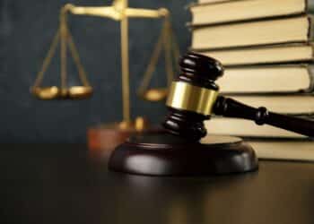 Photo of a gavel on a desk with scales and a stack of books in the background