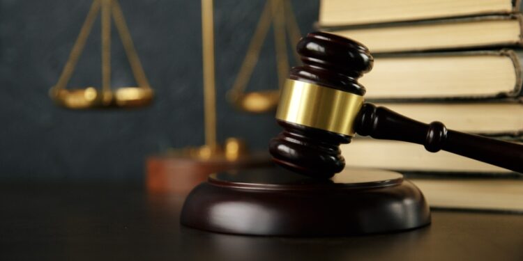 Photo of a gavel on a desk with scales and a stack of books in the background