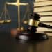 Photo of a gavel on a desk with scales and a stack of books in the background