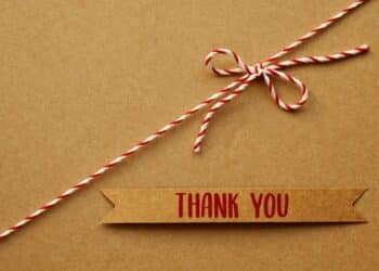 Brown label with "Thank you" in red letters with a red and white string with a bow, all on a brown background