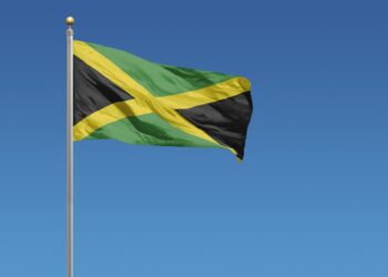 Jamaican flag waving in the wind against a blue background