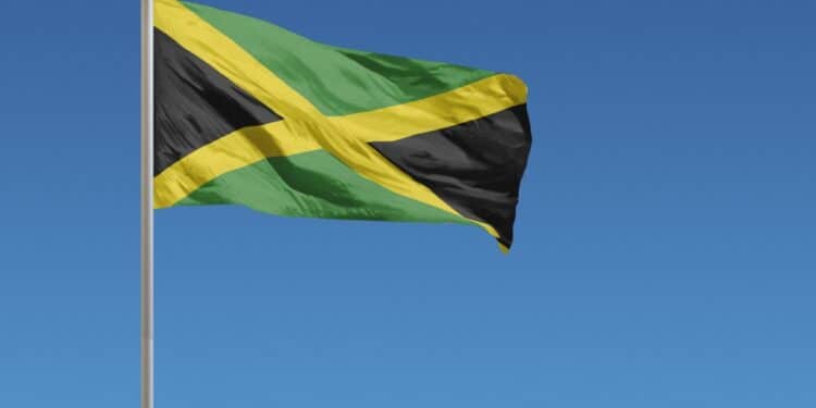 Jamaican flag waving in the wind against a blue background
