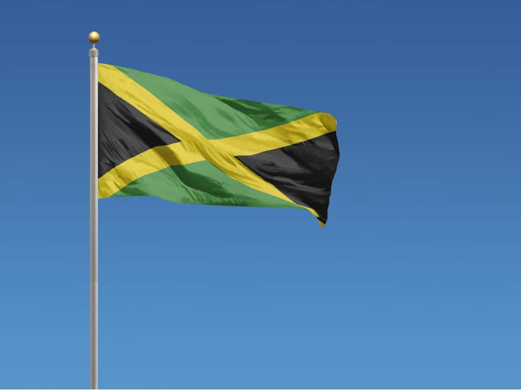 Jamaican flag waving in the wind against a blue background