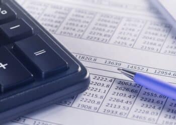 A calculator and pen sitting on top of financial documents