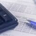 A calculator and pen sitting on top of financial documents