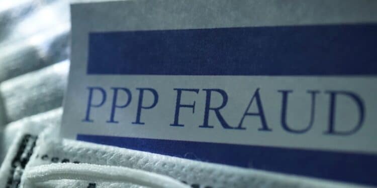 A document with the words "PPP Fraud" laying on a medical facemask.