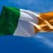 Irish flag waving in the wind against a blue sky
