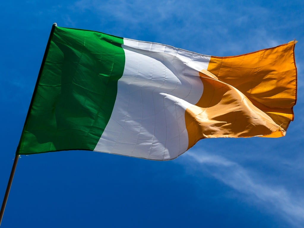 Irish flag waving in the wind against a blue sky