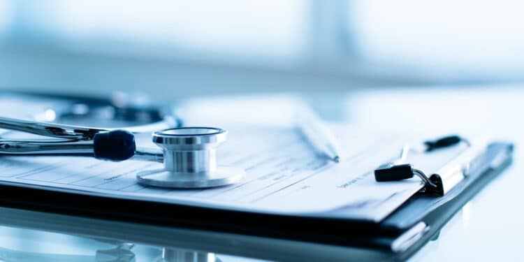 Photo of a stethoscope and a clipboard on a table.
