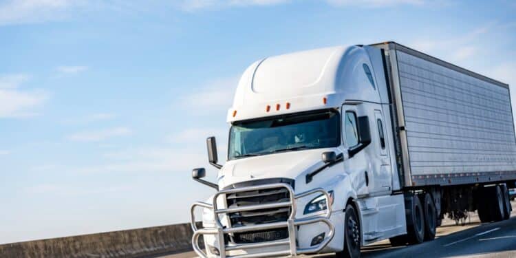 White semitruck driving on a road against a blue sky