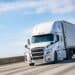 White semitruck driving on a road against a blue sky