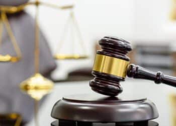 Photo of a gavel with a blurred scales of justice in the background