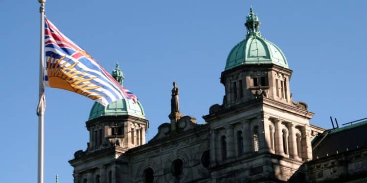 Photo of the B.C. parliament with the B.C. flag in the foreground