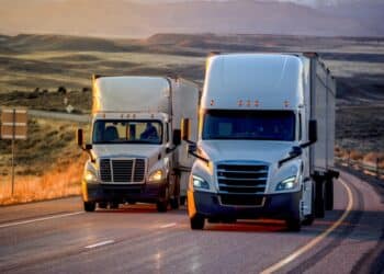 Photo of two white trucks next to each other on a highway