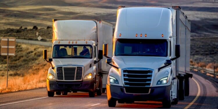 Photo of two white trucks next to each other on a highway