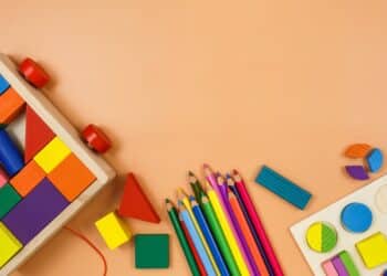 Colorful children's toys like blocks, colored pencils on a tan background