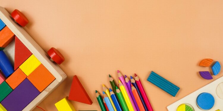 Colorful children's toys like blocks, colored pencils on a tan background
