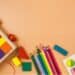 Colorful children's toys like blocks, colored pencils on a tan background
