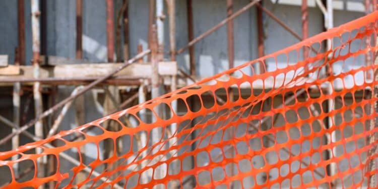 Orange construction net in the foreground and a building under construction in the background