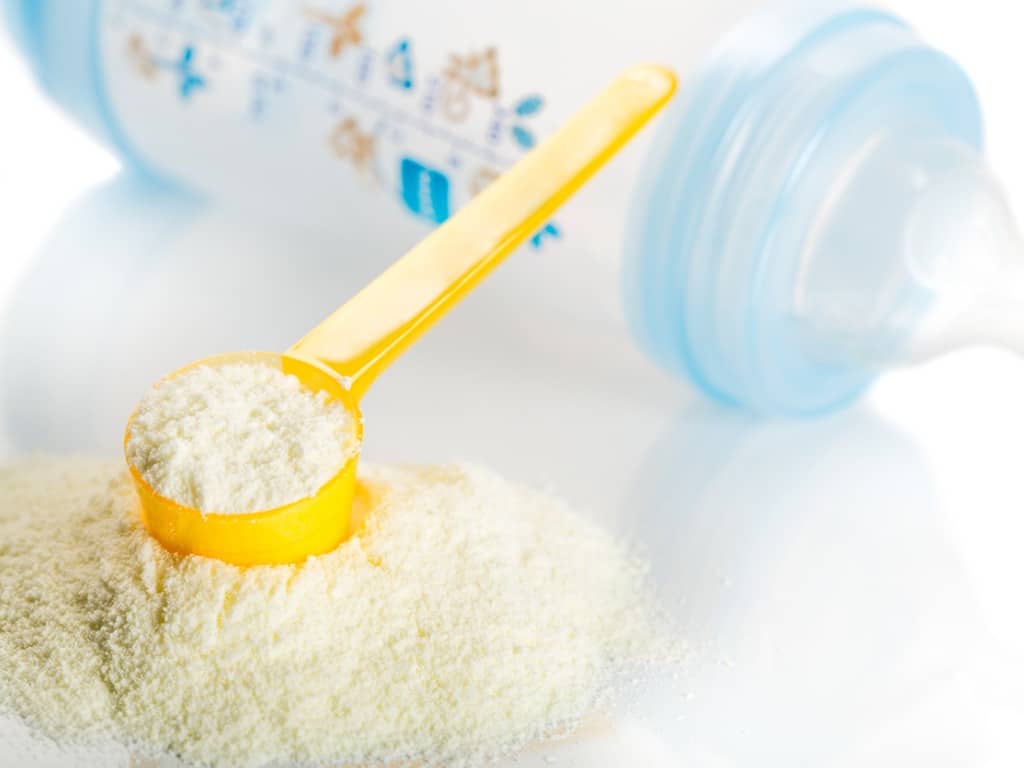 Baby formula with a yellow scoop and a baby bottle