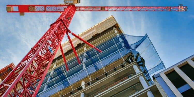 View of an orange crane and a building from a low angle