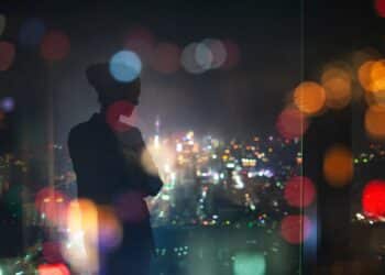 Silhouette of a young woman standing in a building overlooking city lights