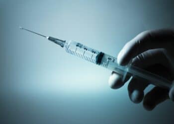 Gloved hand holding a medical syringe