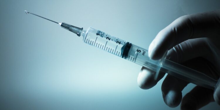 Gloved hand holding a medical syringe