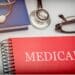 Red book with the words "Medicaid" on it and glasses and a stethoscope