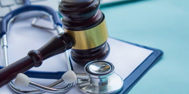 Stethoscope with a gavel and a keyboard in the background