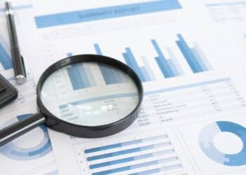 A magnifying laying on blue graphs and charts